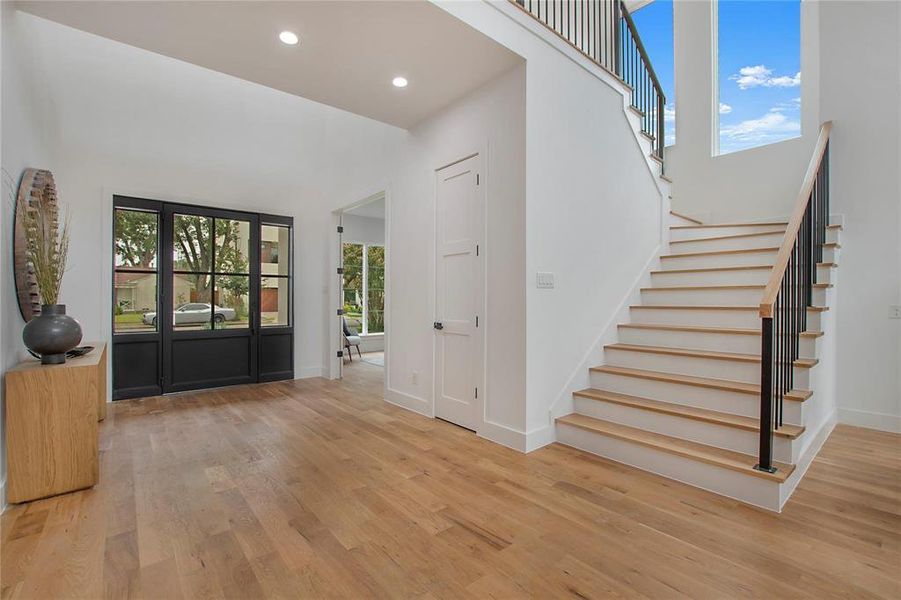 Entrance foyer with light wood-style flooring, stairs, baseboards, recessed lighting, and a towering ceiling Entrance foyer with light wood-style flooring, stairs, baseboards, recessed lighting, and a towering ceiling