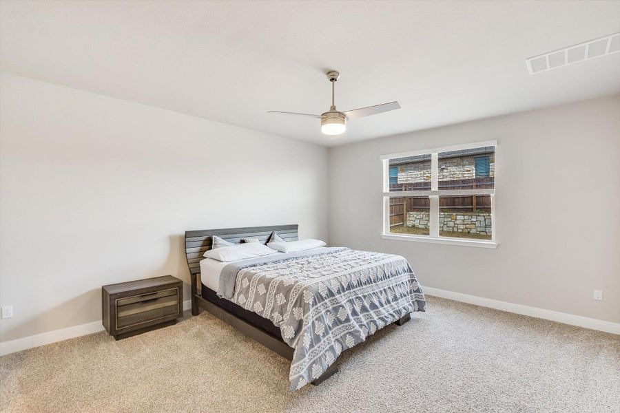 Carpeted bedroom featuring visible vents, ceiling fan, and baseboards