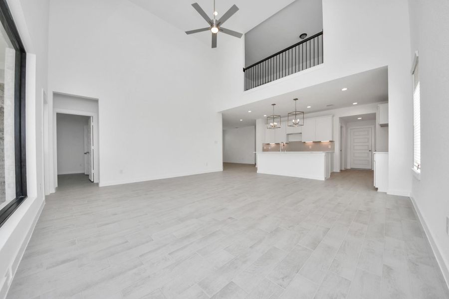 Relax and unwind in this inviting family room, illuminated by abundant natural light streaming in through tall windows, complemented by high ceilings and stunning flooring. Stay comfortable year-round with the gentle breeze from the ceiling fan, creating the perfect atmosphere for family gatherings.