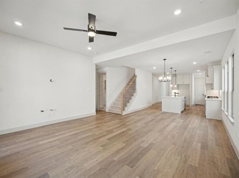 Spacious open-concept living area featuring wood-finish flooring, recessed lighting, and a modern ceiling fan