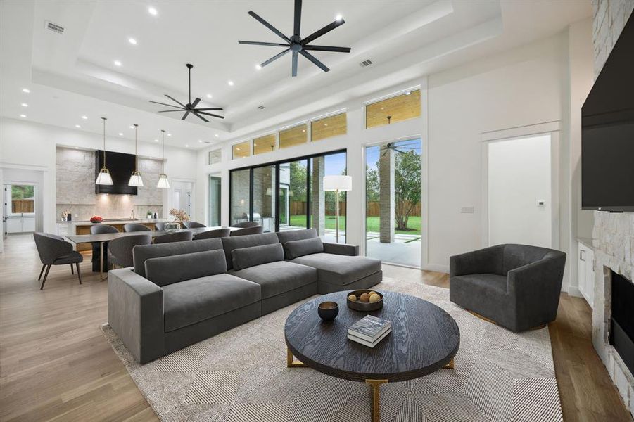 Vitrually Staged area featuring a stone fireplace, a tray ceiling, visible vents, and ceiling fan Vitrually Staged area featuring a stone fireplace, a tray ceiling, visible vents, and ceiling fan