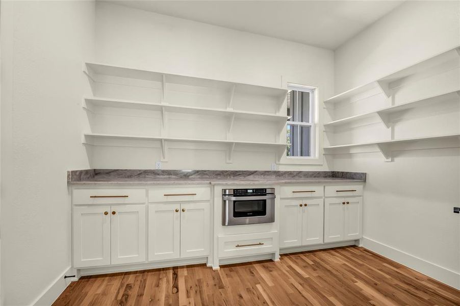 Kitchen with white cabinets, stainless steel oven, light wood finished floors, and open shelves