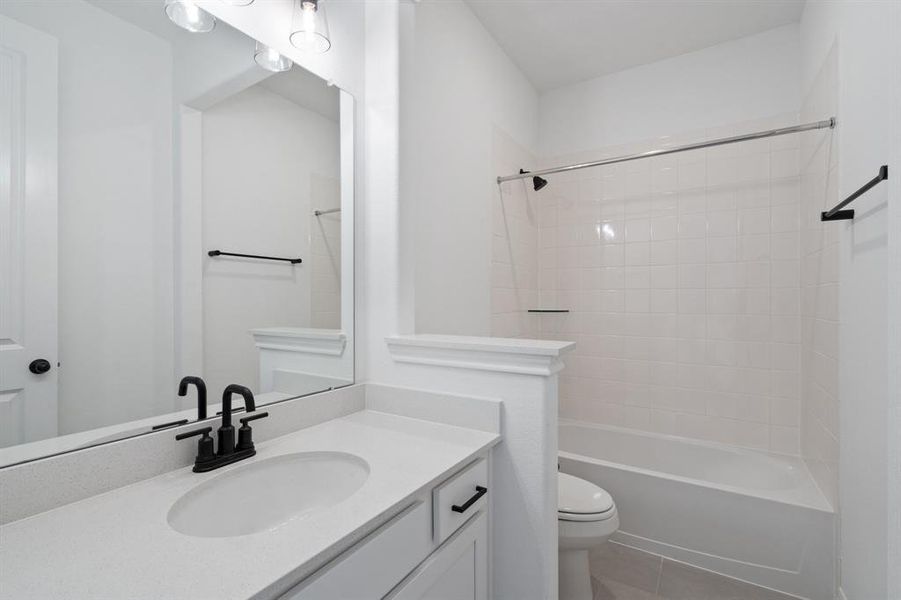 The secondary bath features tile flooring, white cabinetry and light countertops and a shower/tub combo. Perfect for accommodating any visiting family and friends.