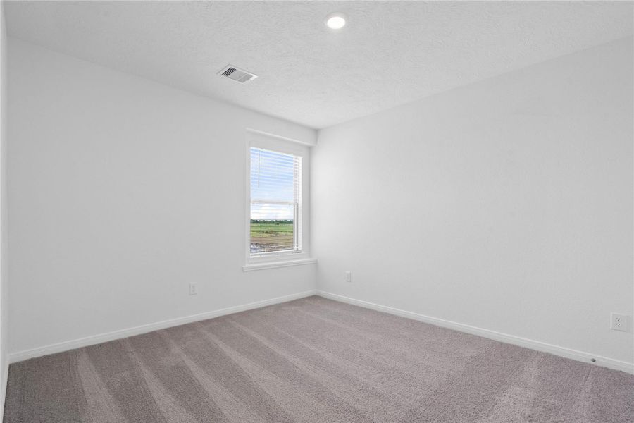 This secondary bedroom offers comfort and style with plush carpeting, neutral paint tones, recessed lighting, large window with blinds, and a generously sized closet.