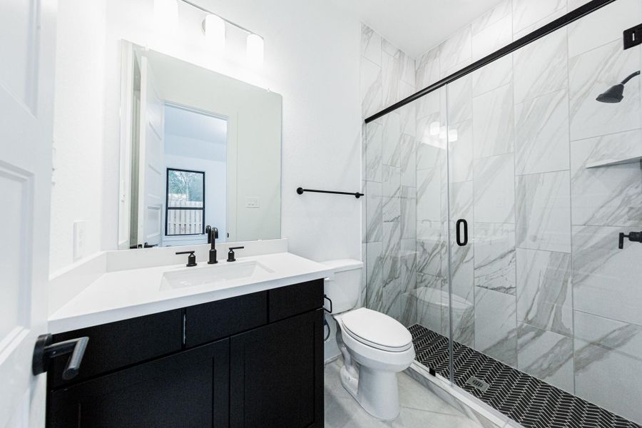 The ensuite secondary bathroom features a modern vanity, large framed walk-in shower, and modern black matte finishes.