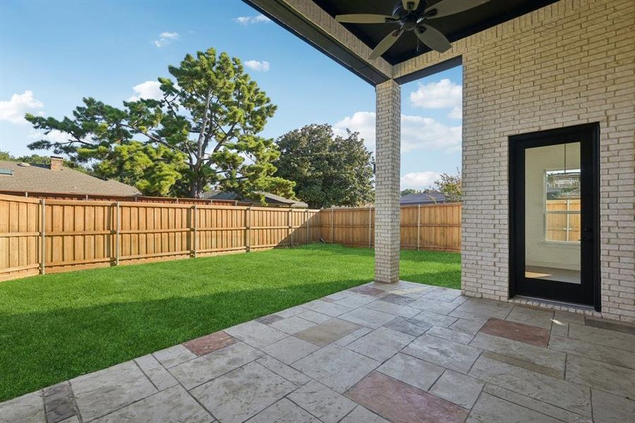 Fenced backyard with a patio area and ceiling fan