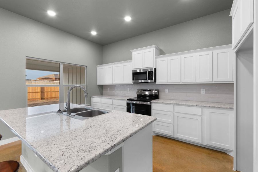 A well-appointed culinary space featuring sleek cabinetry, modern appliances, and a central island with a double sink.