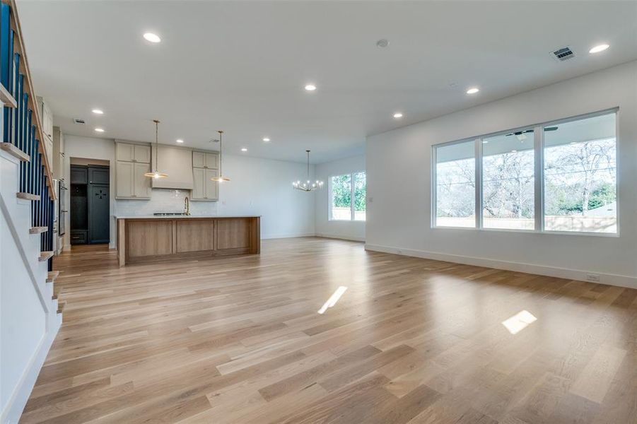 Unfurnished living room with an inviting chandelier and light wood-type flooring