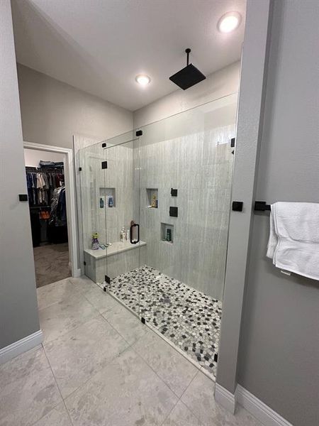 Bathroom with a stall shower, light tile patterned floors, and a walk in closet