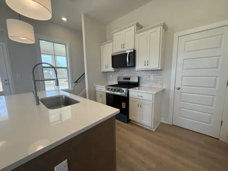 Kitchen featuring stainless steel appliances, white cabinetry, tasteful backsplash, and light wood-style flooring