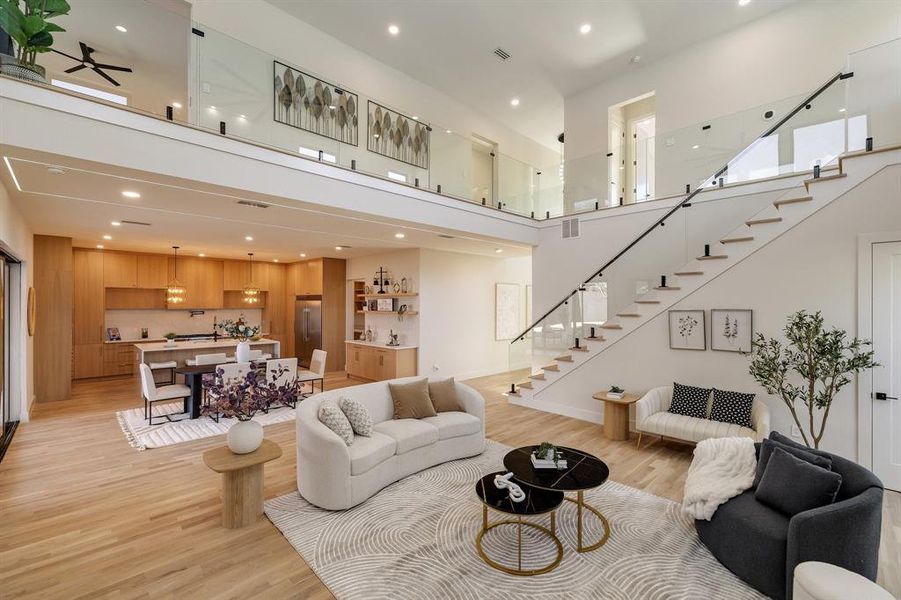 Living room featuring ceiling fan, a high ceiling, and light hardwood / wood-style flooring