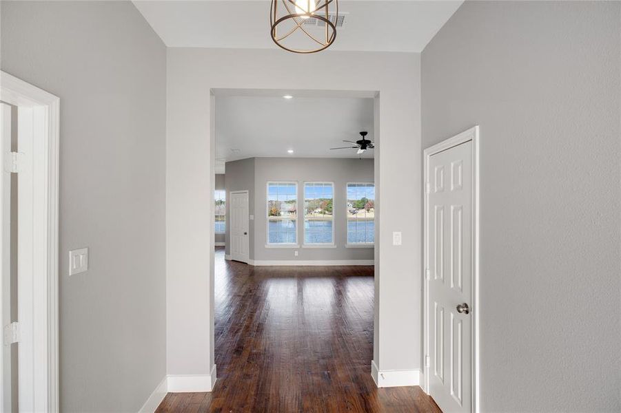 Corridor featuring dark wood finished floors, recessed lighting, a water view, and a chandelier Corridor featuring dark wood finished floors, recessed lighting, a water view, and a chandelier
