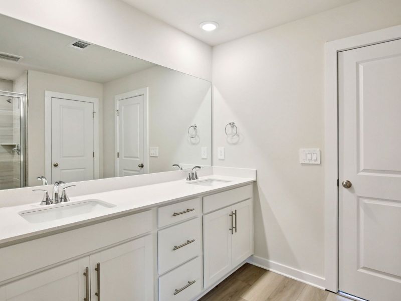 The primary bathroom offers dual vanity sinks and a walk-in shower.