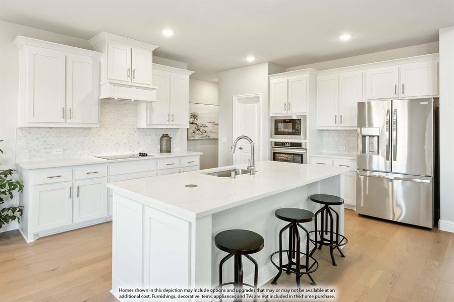White kitchen with large center island, three bar stools, stainless steel appliances, and light hardwood floors