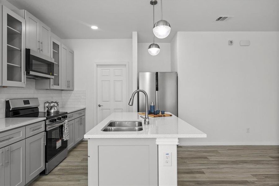 Kitchen featuring visible vents, gray cabinets, a sink, decorative backsplash, and appliances with stainless steel finishes