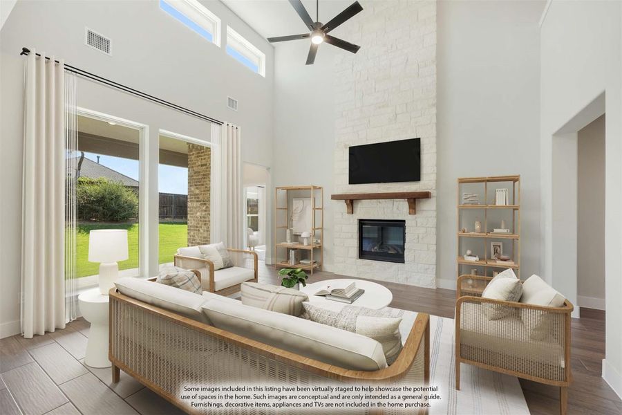 Living room with two-story ceiling, stone fireplace, ceiling fan, and large windows overlooking backyard Living room with two-story ceiling, stone fireplace, ceiling fan, and large windows overlooking backyard