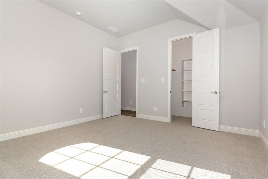 Unfurnished bedroom with light colored carpet and a walk in closet