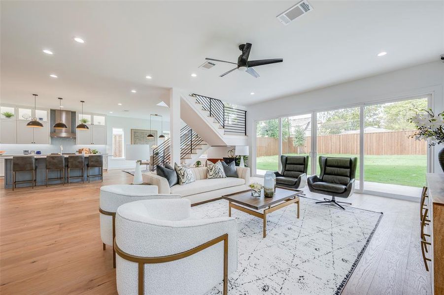 Living area featuring stairs, light wood finished floors, recessed lighting, and ceiling fan Living area featuring stairs, light wood finished floors, recessed lighting, and ceiling fan