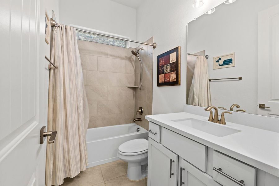 The guest bathroom has a  sleek white vanity with a quartz countertop.