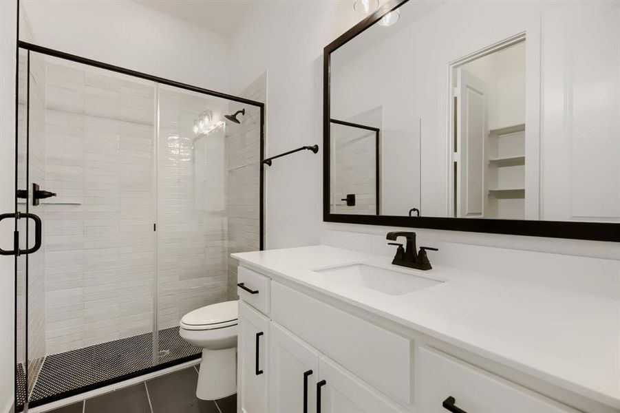 Bathroom featuring vanity, a shower stall, and dark tile patterned flooring