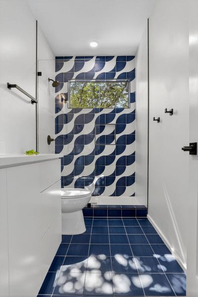 Bathroom featuring dark tile patterned flooring, tile walls, recessed lighting, and a shower
