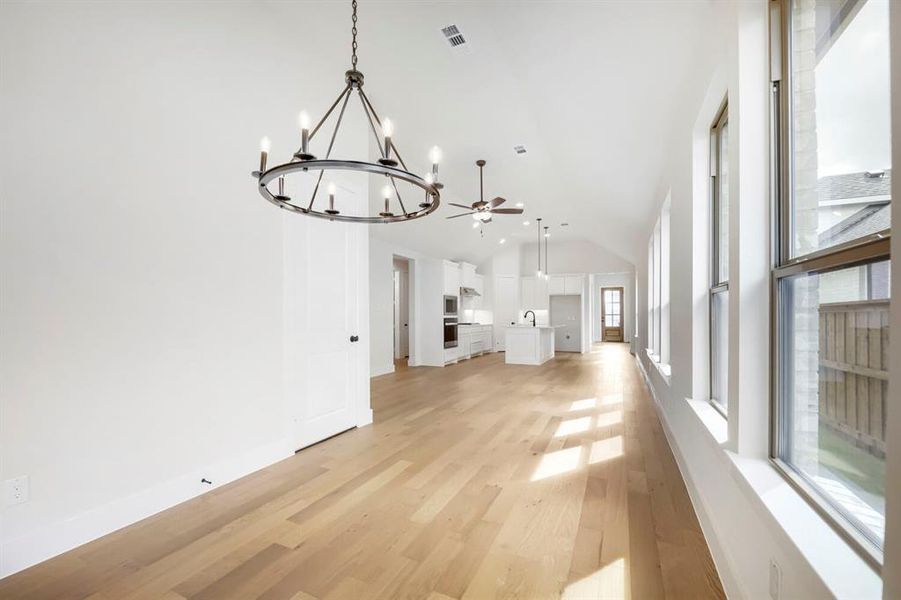 Open-concept interior featuring wood-finish flooring, vaulted ceilings, and an abundance of natural light from multiple windows Open-concept interior featuring wood-finish flooring, vaulted ceilings, and an abundance of natural light from multiple windows