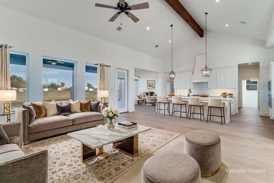 Living room featuring high vaulted ceiling, ceiling fan, beamed ceiling, and light wood-style floors