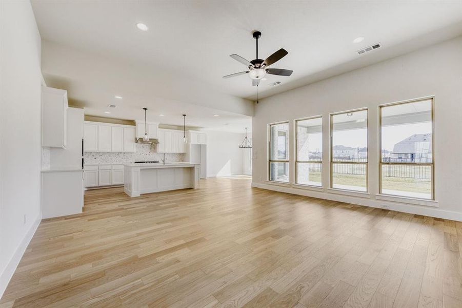 Unfurnished living room featuring ceiling fan, a chandelier, and light wood finished floors