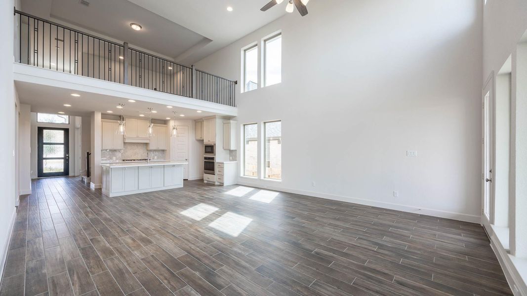 Unfurnished living room featuring healthy amount of natural light, recessed lighting, a towering ceiling, dark wood finished floors, and ceiling fan Unfurnished living room featuring healthy amount of natural light, recessed lighting, a towering ceiling, dark wood finished floors, and ceiling fan