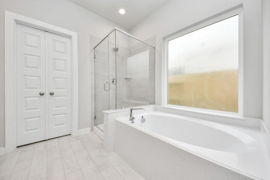Indulge in a spa-like retreat within the confines of this primary bathroom. Delight in a spacious walk-in shower enveloped in stylish tile surround, unwind in a separate garden tub adorned with custom detailing. Sample photo of completed home with similar floor plan. Actual colors and selections may vary. Indulge in a spa-like retreat within the confines of this primary bathroom. Delight in a spacious walk-in shower enveloped in stylish tile surround, unwind in a separate garden tub adorned with custom detailing. Sample photo of completed home with similar floor plan. Actual colors and selections may vary.