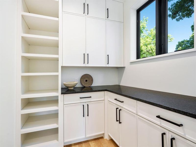 Bar with white cabinets, light wood finished floors, and dark stone counters