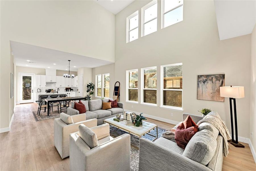 Living room with a notable chandelier, light hardwood / wood-style floors, and a high ceiling