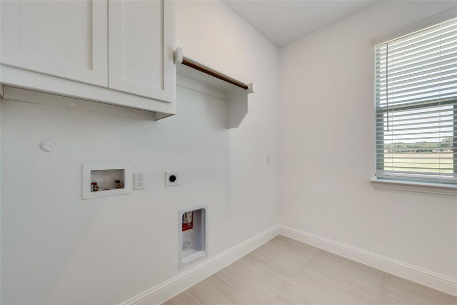 Washroom featuring gas dryer hookup, cabinets, electric dryer hookup, washer hookup, and light tile patterned flooring