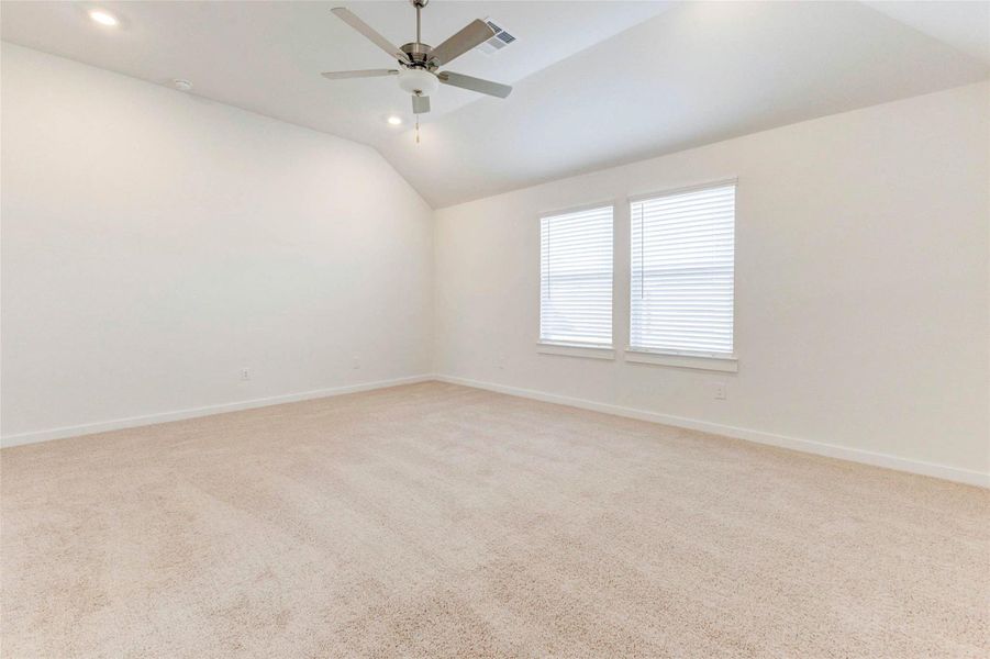 Large windows bathe this primary suite in natural light, highlighting the vaulted ceiling and soft carpeting. The serene design makes it the perfect space to wind down after a long day or enjoy a slow weekend morning. Large windows bathe this primary suite in natural light, highlighting the vaulted ceiling and soft carpeting. The serene design makes it the perfect space to wind down after a long day or enjoy a slow weekend morning.
