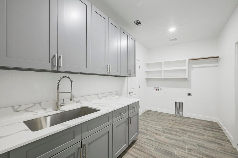 Washroom with cabinet space, electric dryer hookup, washer hookup, and light wood-type flooring