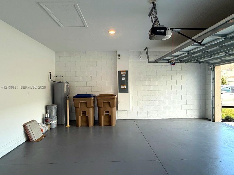 Garage with painted concrete block walls, overhead door opener, and finished floor surface