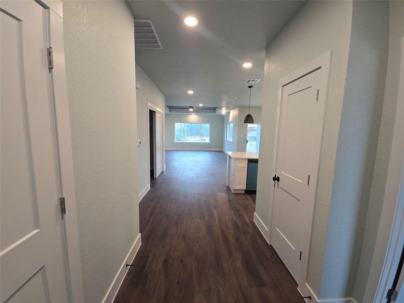 Hallway with dark wood finished floors, recessed lighting, and a textured wall