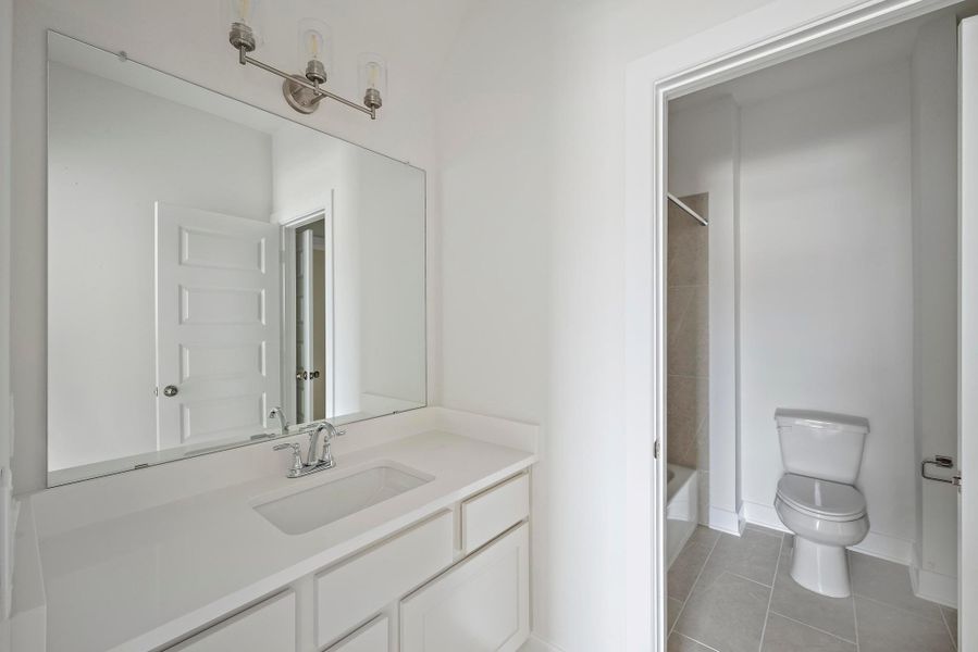 Bathroom featuring vanity, shower / bathtub combination, toilet, baseboards, and tile patterned floors Bathroom featuring vanity, shower / bathtub combination, toilet, baseboards, and tile patterned floors