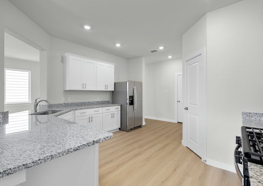 Large kitchen includes white cabinetry, Whirlpool brand appliances and granite counters.