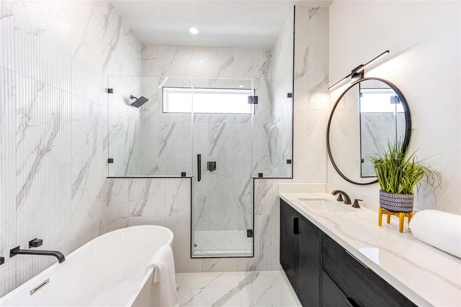 Primary bathroom featuring double vanity sinks with quartz countertops, adjustable anti-fog mirrors, and tile flooring. Highlights include 10-ft ceilings, a freestanding soaking tub, chandelier accent lighting, and a frameless shower with floor-to-ceiling tile.