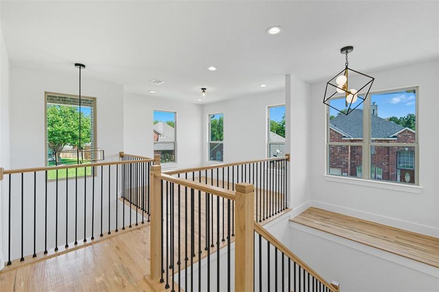 Corridor with a chandelier, light wood-style floors, recessed lighting, and an upstairs landing