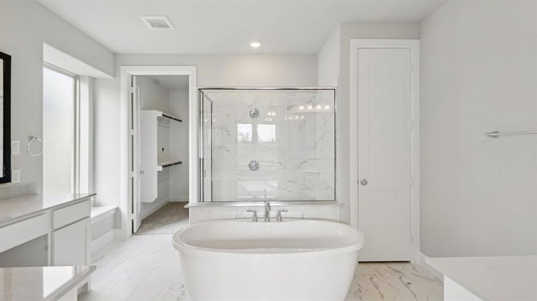 Full bathroom with a marble finish shower, a freestanding tub, vanity, light marble finish flooring, and recessed lighting Full bathroom with a marble finish shower, a freestanding tub, vanity, light marble finish flooring, and recessed lighting