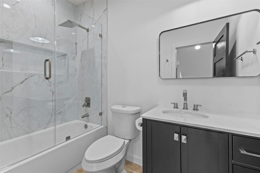 Full bathroom featuring vanity, enclosed tub / shower combo, and light wood finished floors