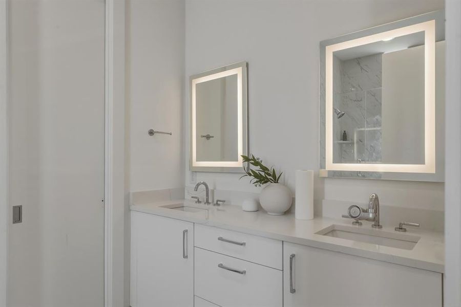 Full bathroom featuring double vanity and a marble finish shower