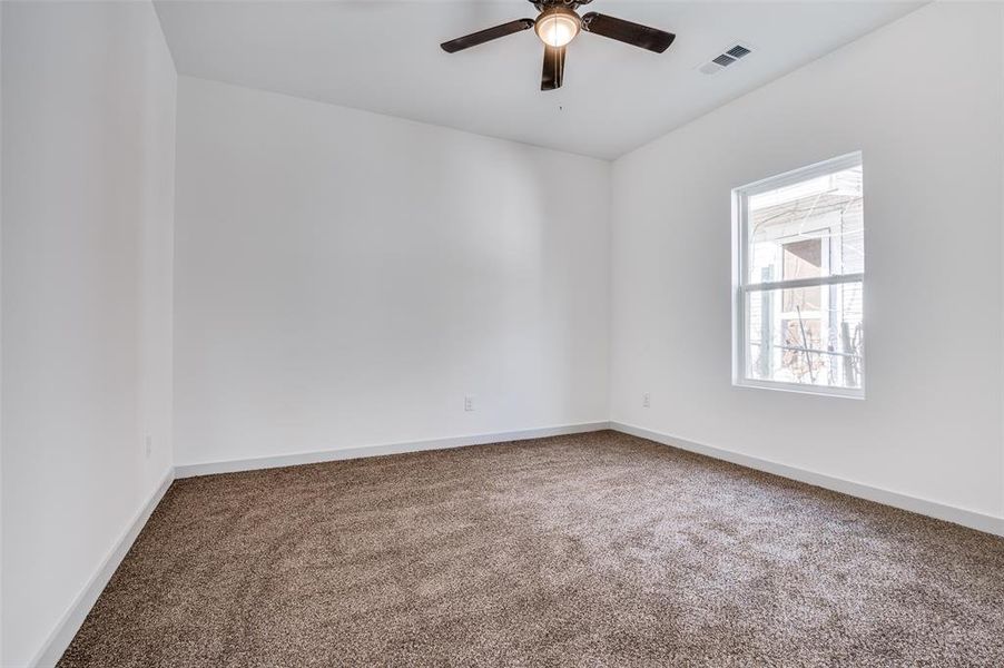 Unfurnished room featuring visible vents, carpet flooring, baseboards, and ceiling fan