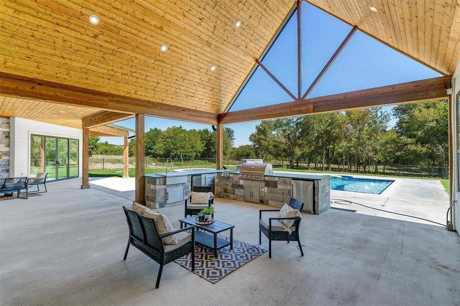 View of patio featuring exterior kitchen, grilling area, a fenced in pool, and a gazebo