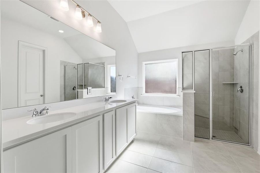 Bathroom with vaulted ceiling, a bath, double vanity, a stall shower, and light tile patterned floors
