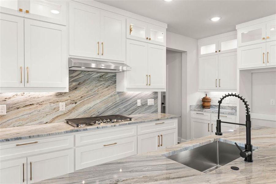 Kitchen with glass insert cabinets, white cabinetry, and recessed lighting Kitchen with glass insert cabinets, white cabinetry, and recessed lighting