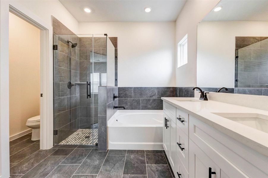 This beautifully designed primary bath features a spacious glass-enclosed shower with stylish tile surround and modern fixtures. Adjacent to the shower, the soaking tub offers a perfect place to relax and unwind. The thoughtful layout combines both functionality and elegance, creating a spa-like experience within the comfort of your own home.