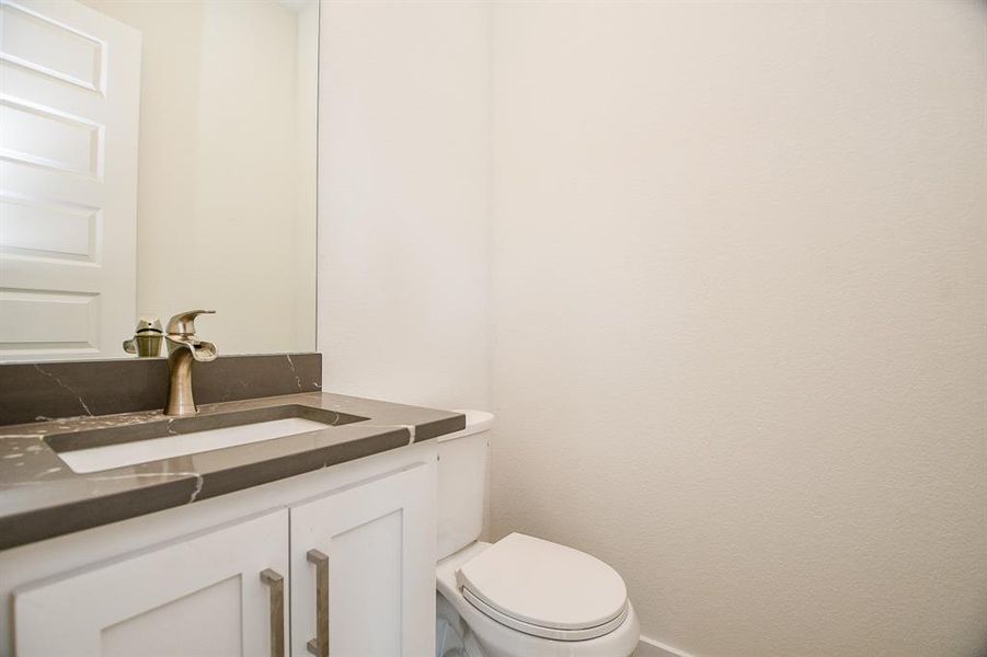 View of the powder room featuring a beautiful vanity with quartz tops.